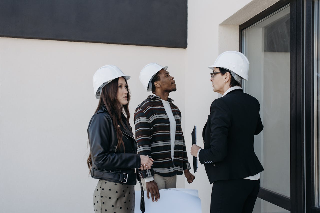 why-choose-us A diverse group of professionals in construction helmets reviewing property plans outdoors.