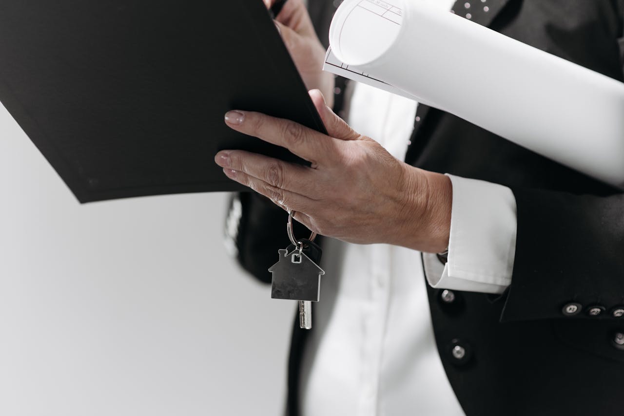 portfolio-01 Close-up of a business professional holding a house key and architectural plans, symbolizing real estate.