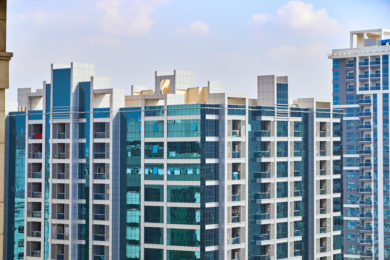 portfolio-02 A cityscape view of modern high-rise buildings with reflective glass facades under a blue sky.